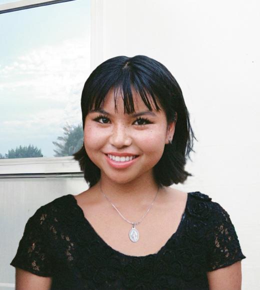 Smiling young woman with short black hair, silver pendant necklace, black top